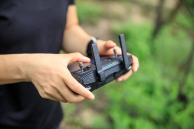 People remote control a flying drone in summer forest