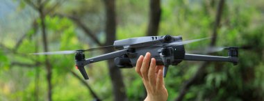 Hand reaching out for a a flying drone in summer forest