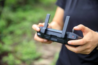 People remote control a flying drone in summer forest