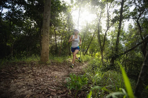 Kadın koşucu orman yolunda koşuyor.