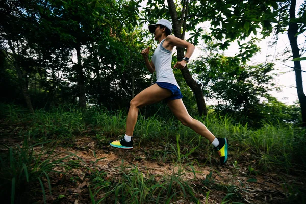 Kadın koşucu orman yolunda koşuyor.