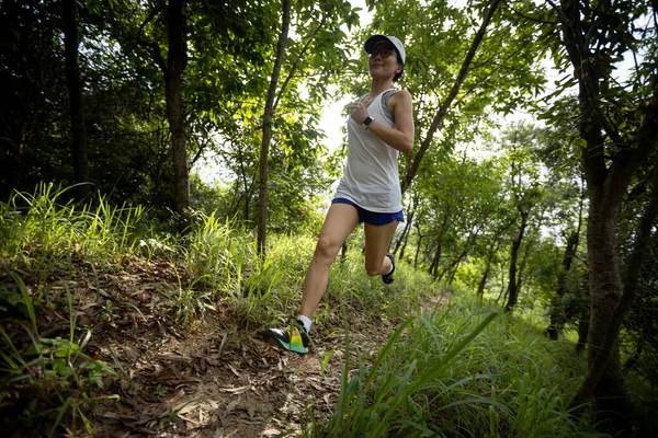 Woman runner running on forest trail