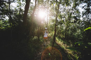 Kadın koşucu orman yolunda koşuyor.