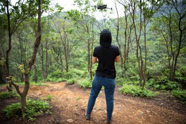 People remote control a flying drone in summer forest