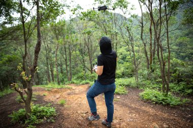 People remote control a flying drone in summer forest