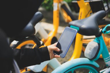 Akıllı telefon kullanan eller, şehirdeki paylaşılan motorun QR kodunu tarıyor