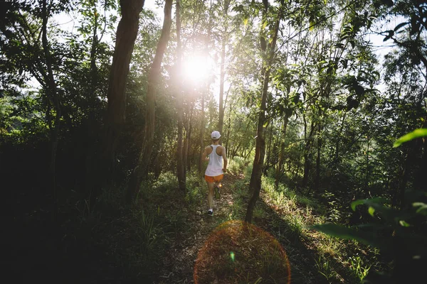 Kadın koşucu orman yolunda koşuyor.