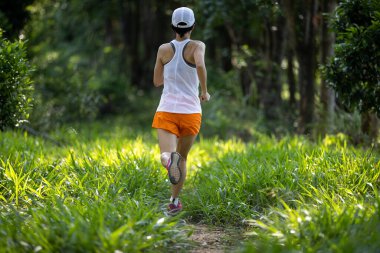 Trail runner running in summer forest trail