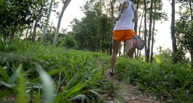 Woman trail runner running at tropical forest mountain peak