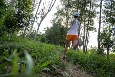 Woman trail runner running at tropical forest mountain peak