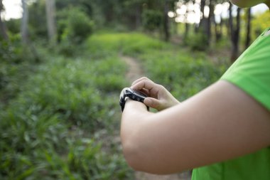 Woman trail runner set the sports watch in forest
