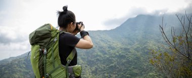 Kadın fotoğrafçı bahar dağında fotoğraf çekiyor.