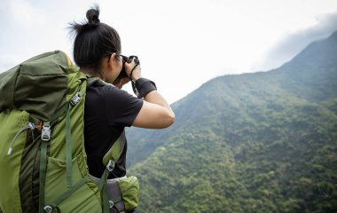 Kadın fotoğrafçı bahar dağında fotoğraf çekiyor.