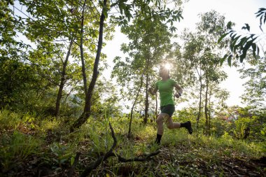 Woman trail runner running at sunrise tropical forest mountain peak