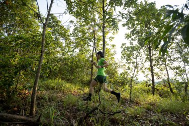 Woman trail runner running at sunrise tropical forest mountain peak