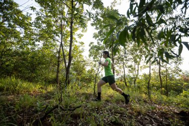 Woman trail runner running at sunrise tropical forest mountain peak