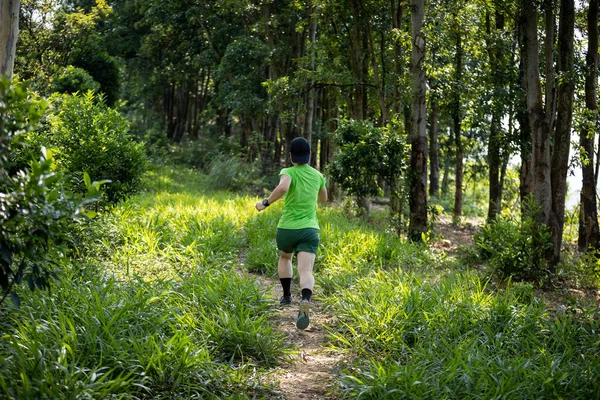 Woman trail runner running at tropical forest mountain peak