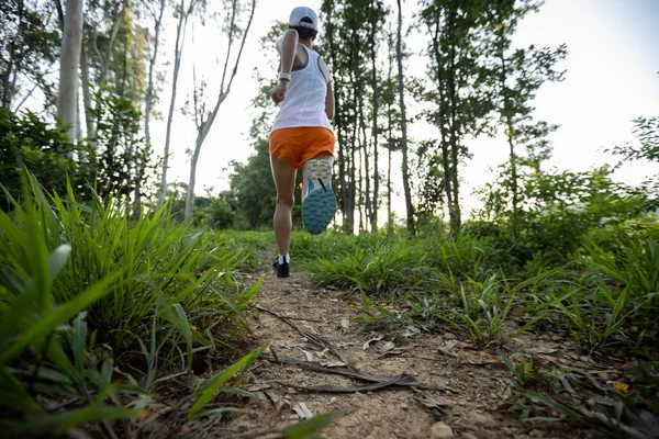 Woman trail runner running at tropical forest mountain peak