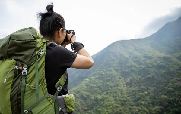 Kadın fotoğrafçı bahar dağında fotoğraf çekiyor.