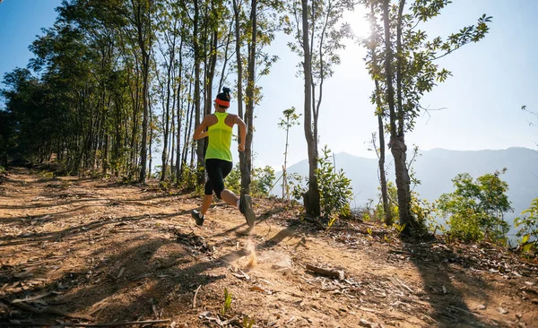 Woman trail runner running at sunrise tropical forest mountain peak