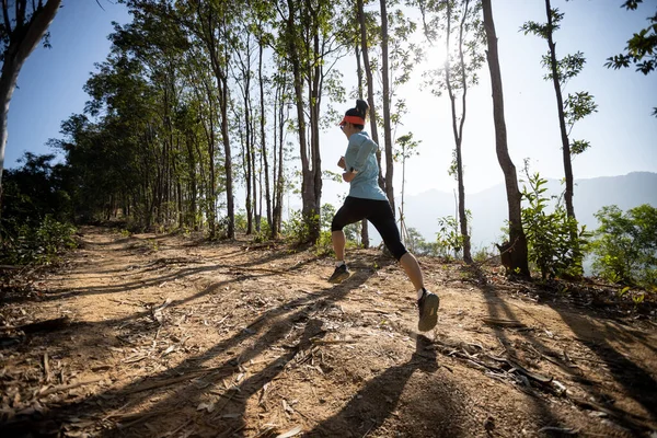 Woman trail runner running at sunrise tropical forest mountain peak
