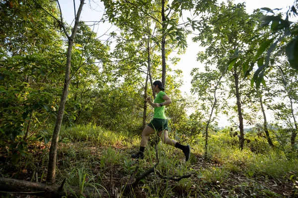 Woman trail runner running at sunrise tropical forest mountain peak