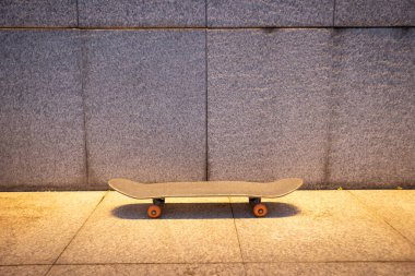 Skateboard and illuminated gray wall in city