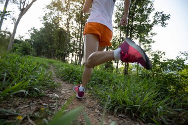 Woman trail runner running at tropical forest mountain peak