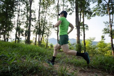 Woman trail runner running at tropical forest mountain peak