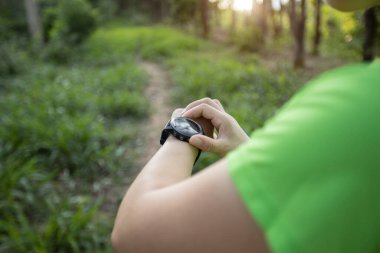 Woman trail runner set the sports watch in forest