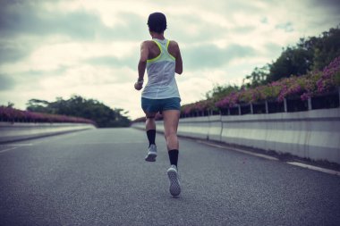 Fitness woman runner running on city bridge road