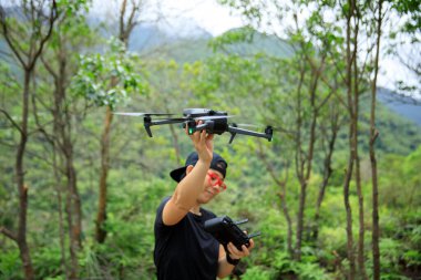 People remote control a flying drone in summer forest