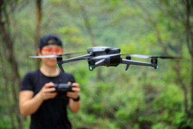 People remote control a flying drone in summer forest
