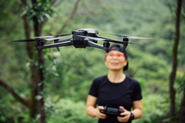 People remote control a flying drone in summer forest