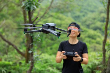 People remote control a flying drone in summer forest