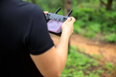 People remote control a flying drone in summer forest