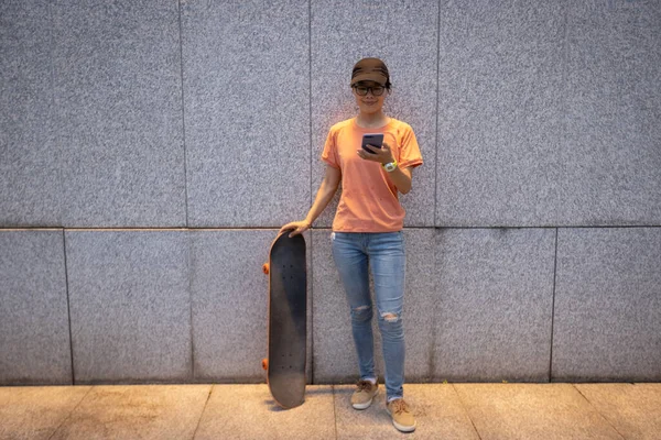 Female Skateboarder Using Smartphone Leaning Wall City — Stock fotografie