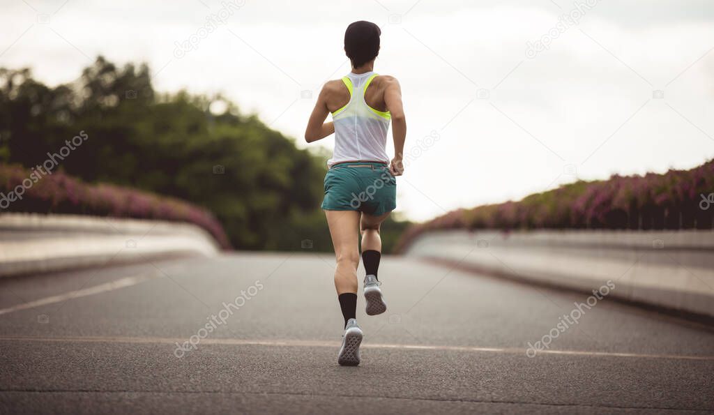 Fitness woman runner running on city bridge road