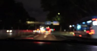 Woman driving car on city road at night