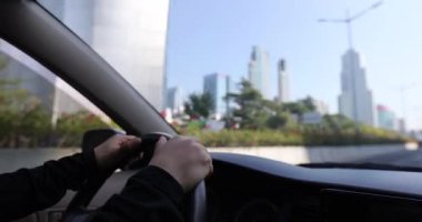 Kadın şehir yolunda araba sürüyor.