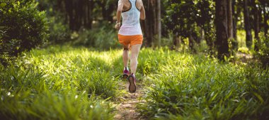 Trail runner running in summer forest trail