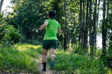 Woman trail runner running at tropical forest mountain peak