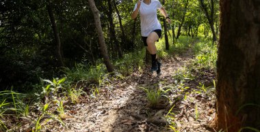Trail runner running in summer forest trail
