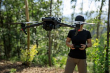 People remote control a flying drone in summer forest
