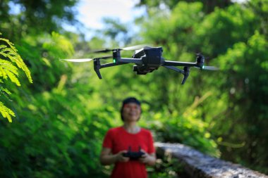 People remote control a flying drone in summer forest