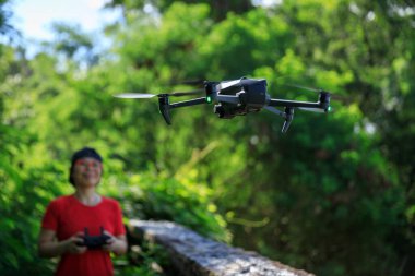 People remote control a flying drone in summer forest
