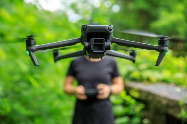 People remote control a flying drone in summer forest