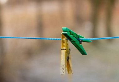 Close-up of a snowy plastic clothespin on a blue clothesline outdoor in winter
