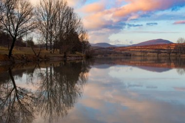 Sunset over lake with colorful clouds reflected on the water