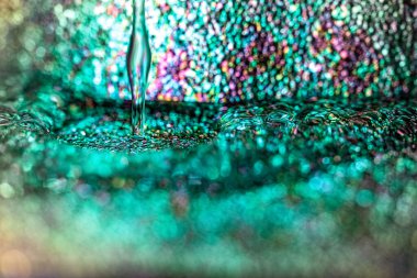 Yeşil parıltı üzerine su damlası, parlak bokeh ile bulanık arkaplan